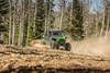 Front angle of a person and passengers driving a side x side off-road through trees.