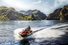 Three-quarter front angle of a person riding a personal watercraft on a lake.