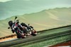 Three-quarter front angle of a person riding a motorcycle around a curve on a racetrack.