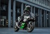 Three-quarter front angle of a person riding a motorcycle in a city.