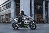 Side angle of a person riding a motorcycle in a city.