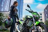 Three-quarter front angle of a parked motorcycle next to a person.