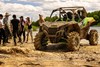 Three-quarter front angle of a side x side off-road with people standing around.