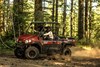 Side angle of two people driving a side x side off-road.